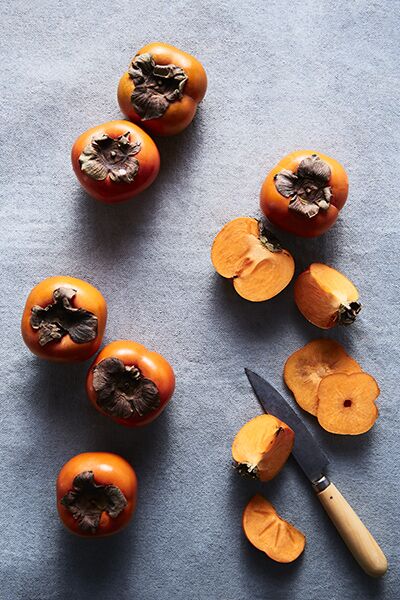 still life of persimmons with knife overhead shot