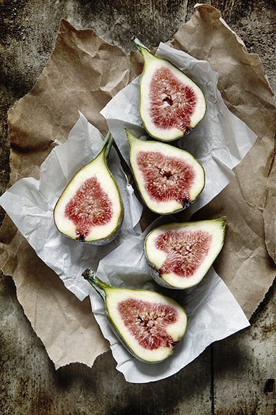Fresh figs cut in half on paper and a wooden board