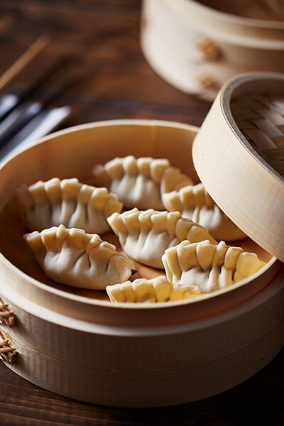 Raw Chinese dim sum dumplings set in a bamboo steamer